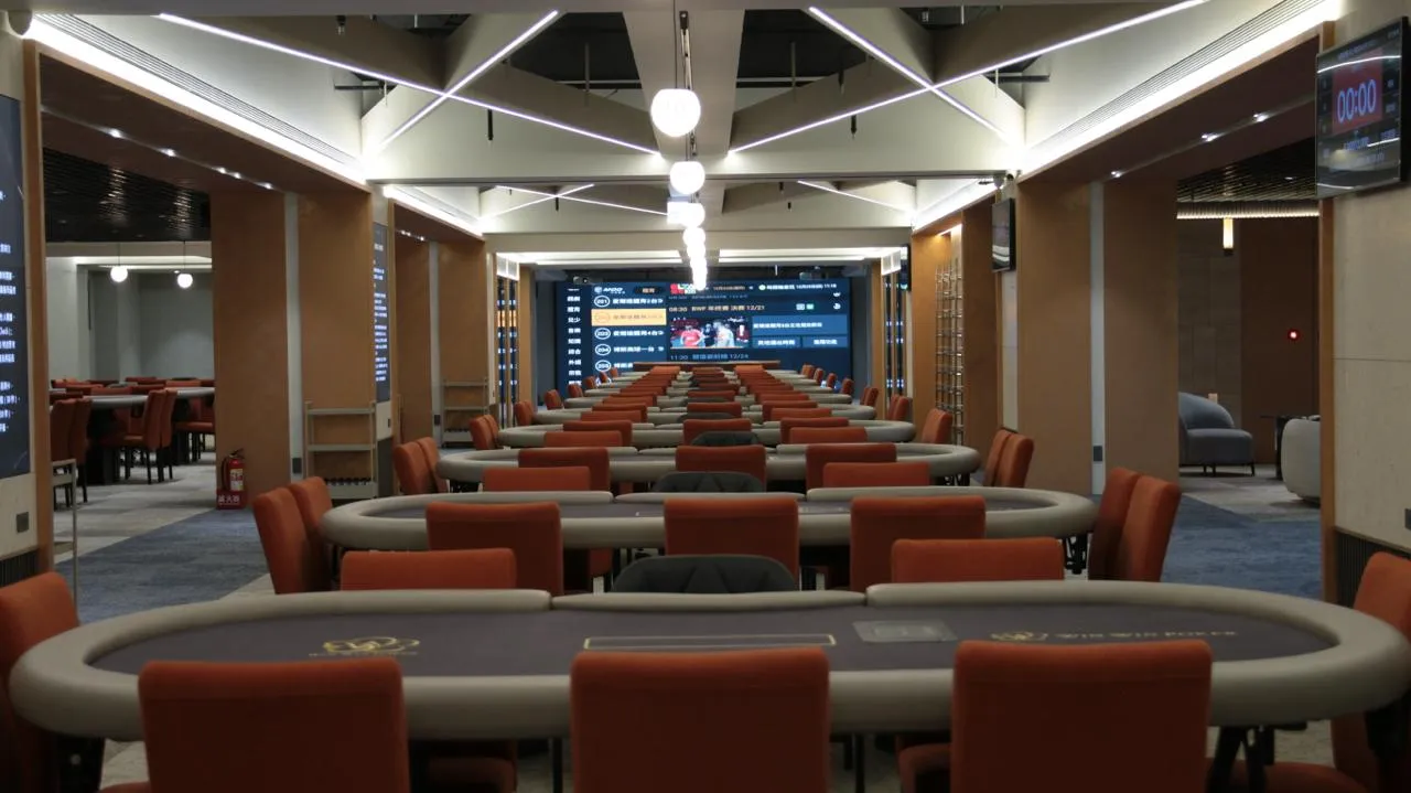 Win Win Poker 旗艦館主賽場，多張牌桌並排，走道底端是賽事看板