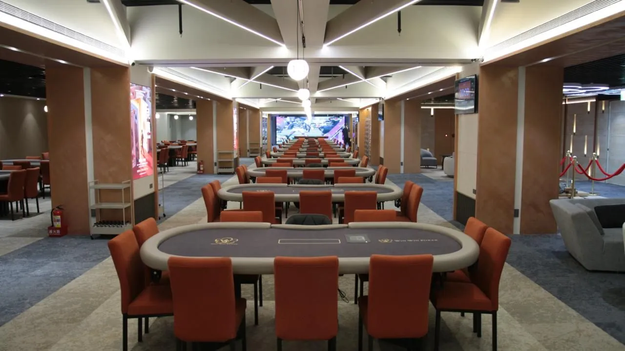 Win Win Poker 旗艦館的大廳賽場，橘色座椅的牌桌一路排到底端的大螢幕
